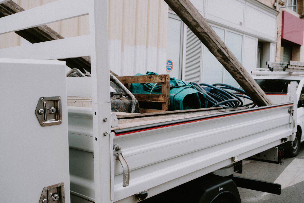 A white construction truck loaded with building materials and equipment parked by a building.